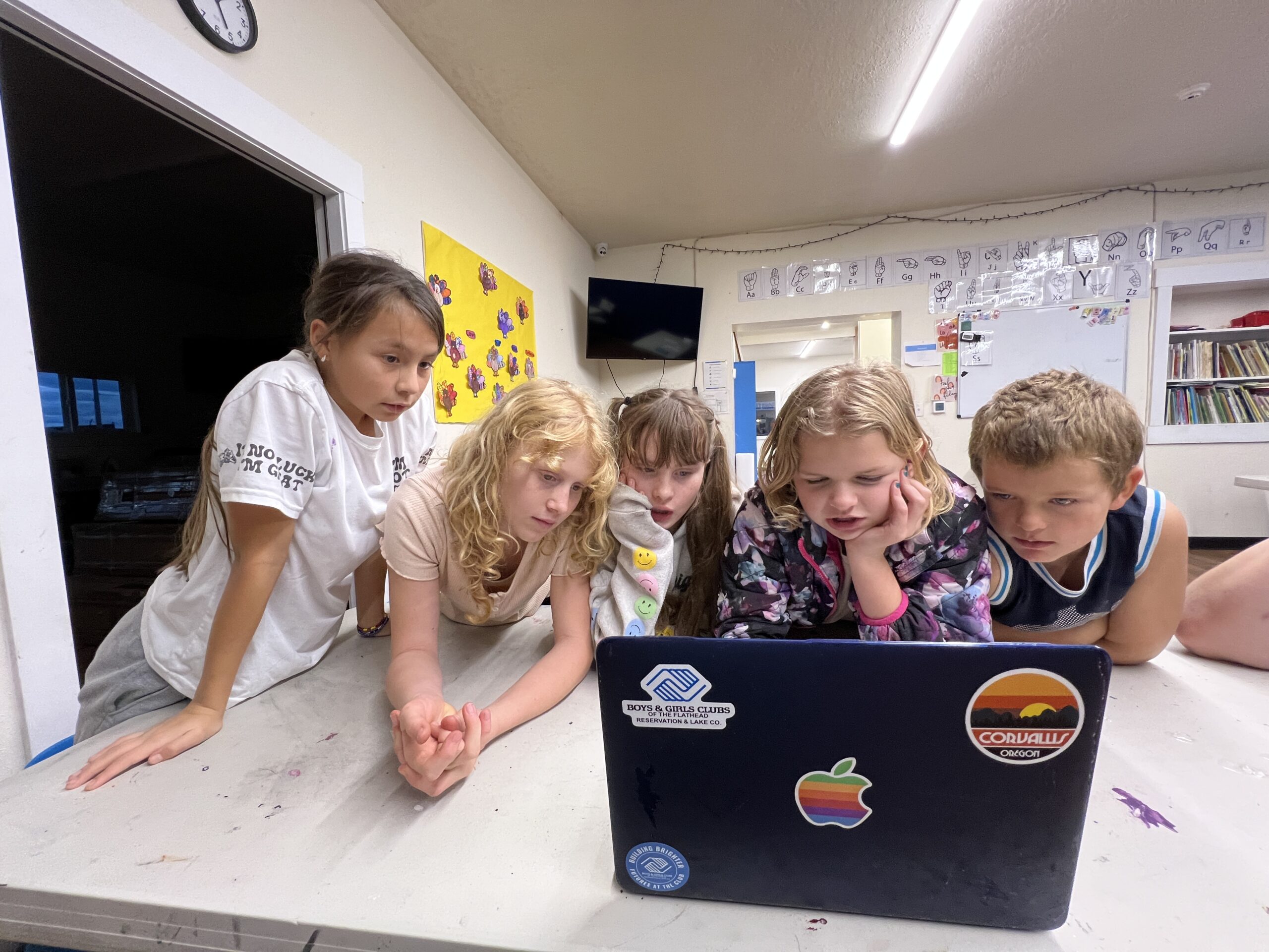 young learners gathered around a laptop