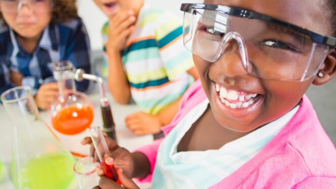 Children with big excited smiles conducting a chemistry experiment.