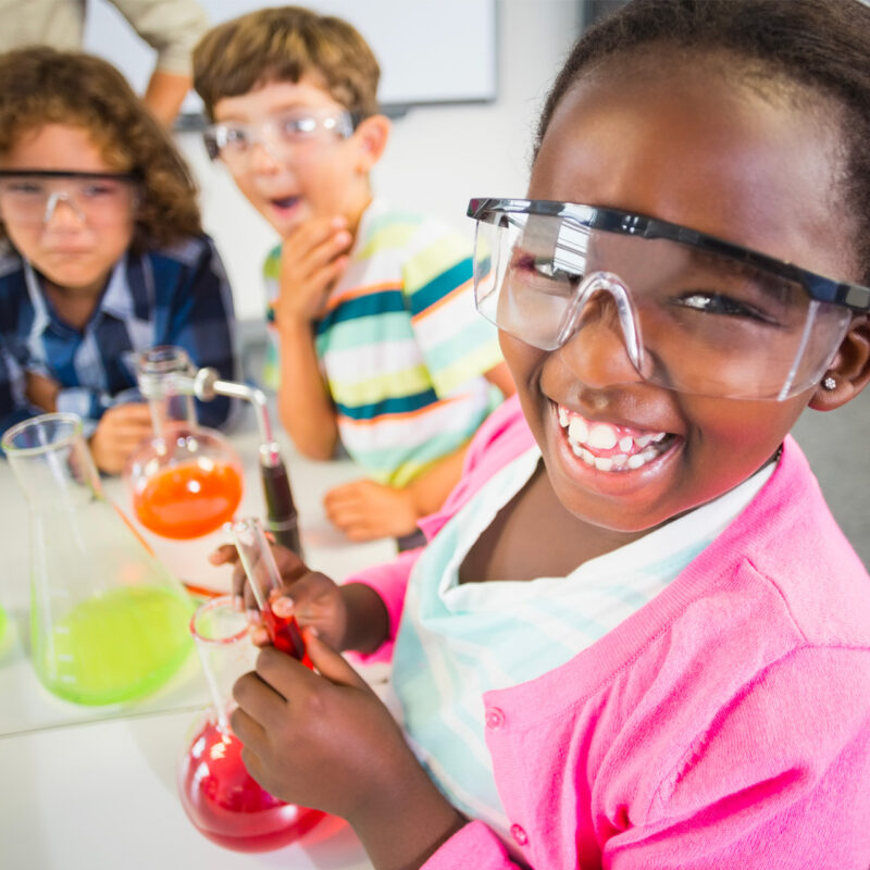 Children with big excited smiles conducting a chemistry experiment.