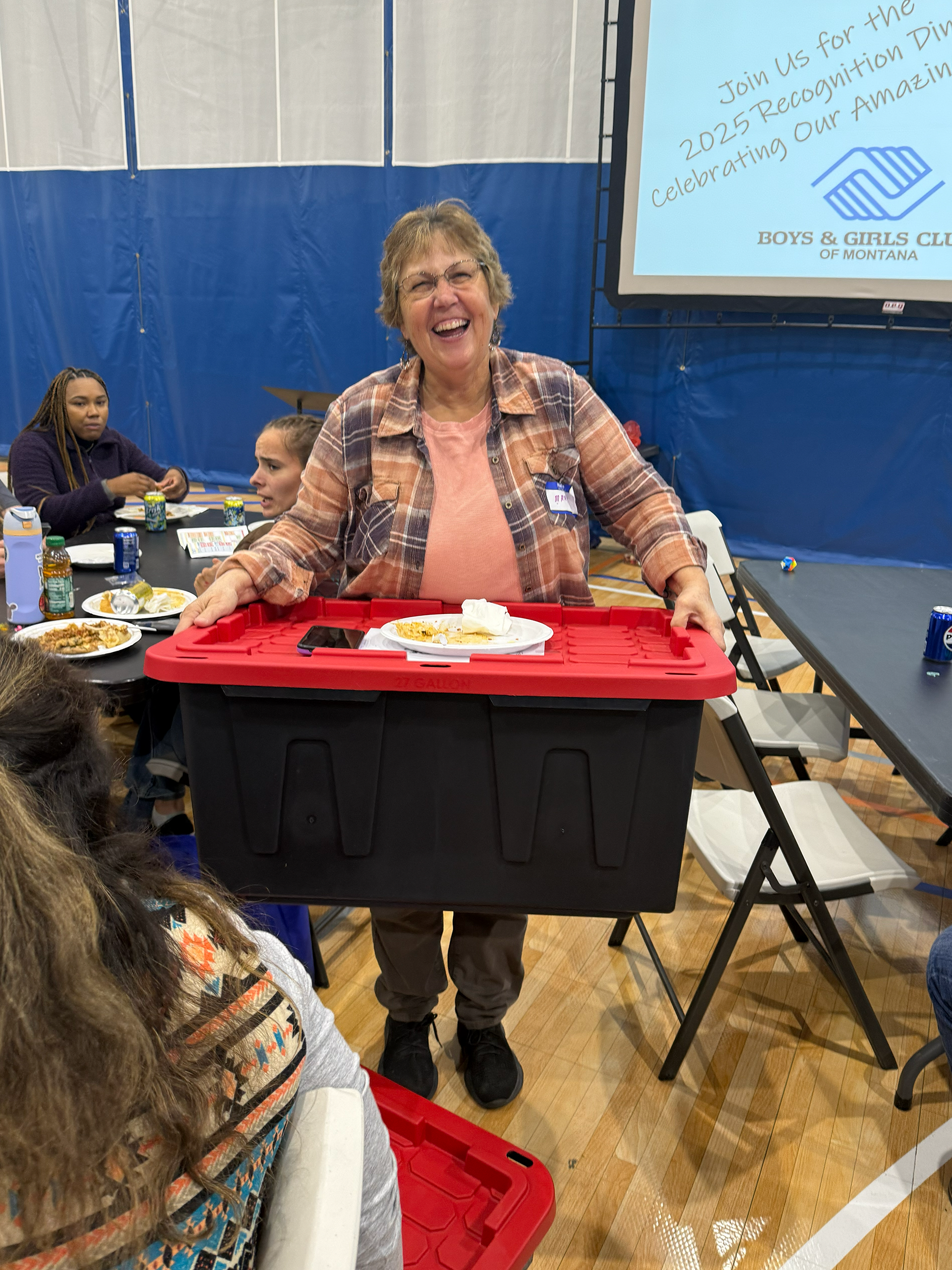 A Boys and Girls Club staff member holds a large AI Tool Kit box with a smile on her face.